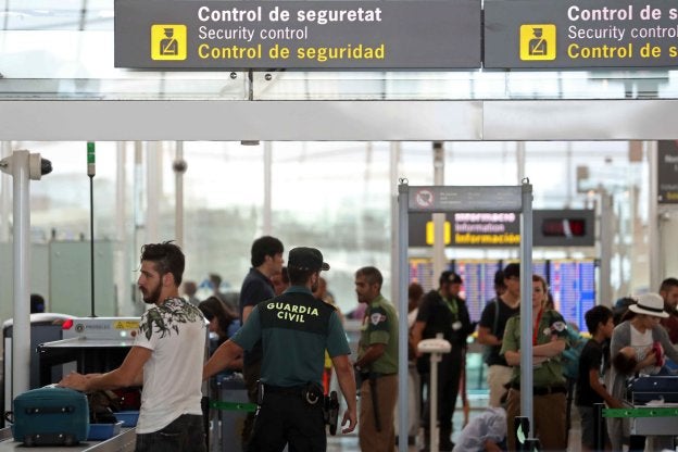 Varias personas pasan los controles de seguridad de El Prat ayer al mediodía, supervisados por la Guardia Civil y vigilantes de Eulen. :: T. A. / efe