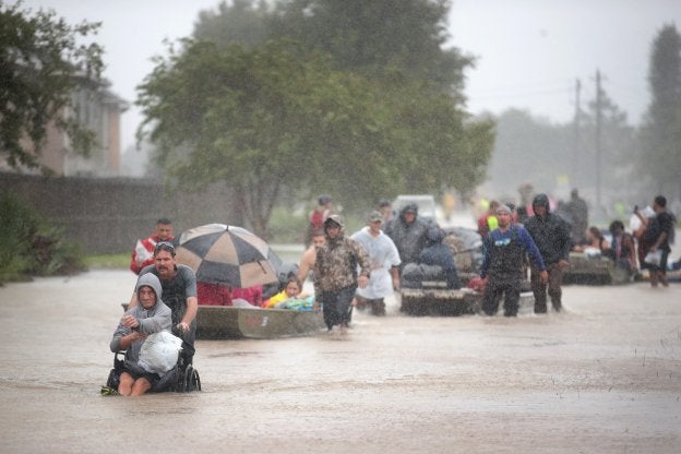 Un grupo de personas abandona sus hogares caminando y en barcas en Houston. :: S. Olson / AFP