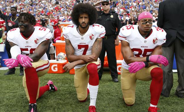 Colin Kaepernick, en medio, escoltado por dos compañeros hace unos meses.