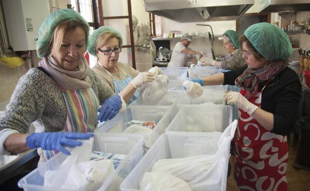 Algunas de las mujeres que colaboran con la asociación preparan bolsas con comida./FRANCIS SILVA