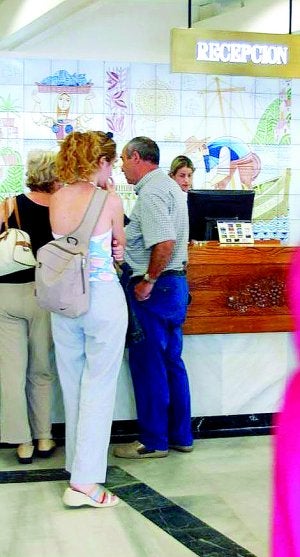 Turistas esperan a registrarse en la recepción de un hotel. ::
SUR/
