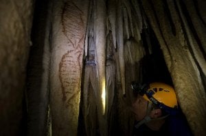 Un arqueólogo observa dos de las pinturas rupestres en las que se tomaron ayer muestras de cal. :: Sur/